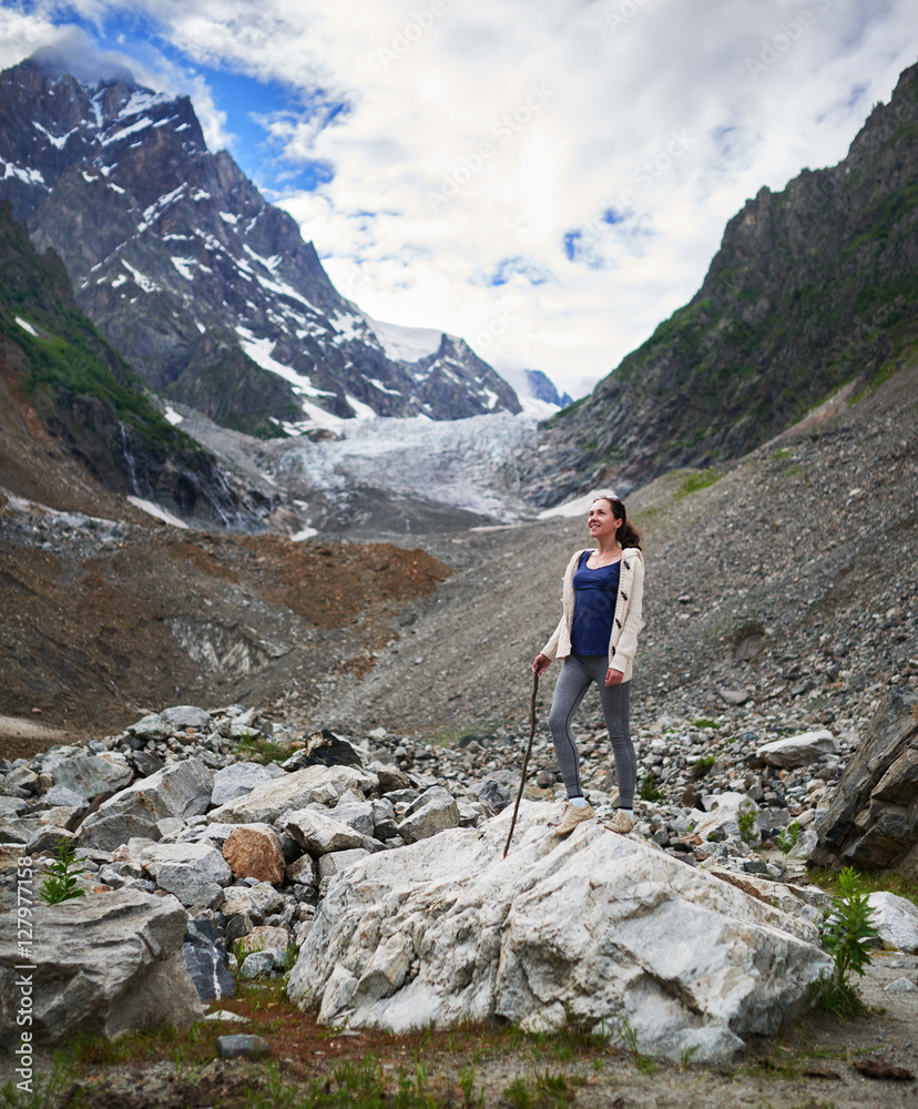 Girl in hike to the glacier, stands on a rock