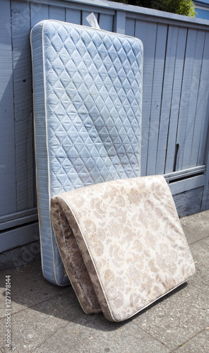 Abandoned mattresses leaning against fence. Vertical. photo