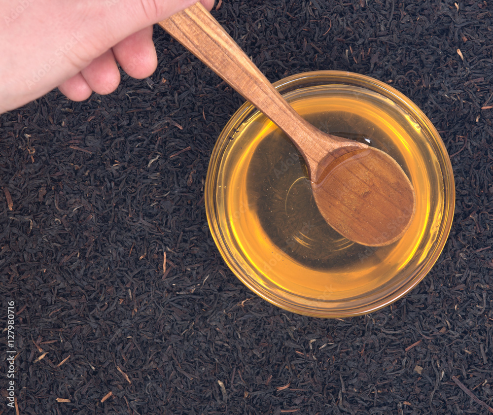 Organic amish farm pure honey in bowl and camellia assam tea with wooden spoon Organic amish farm pure honey in bowl and camellia assam tea with wooden spoon