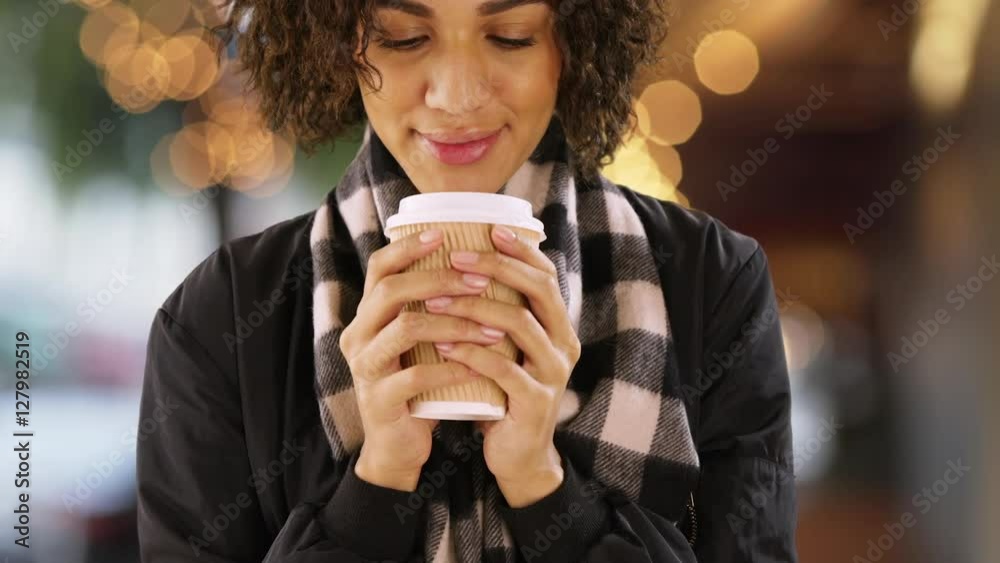 Cute African woman holding coffee cup outdoors, holding paper cup.