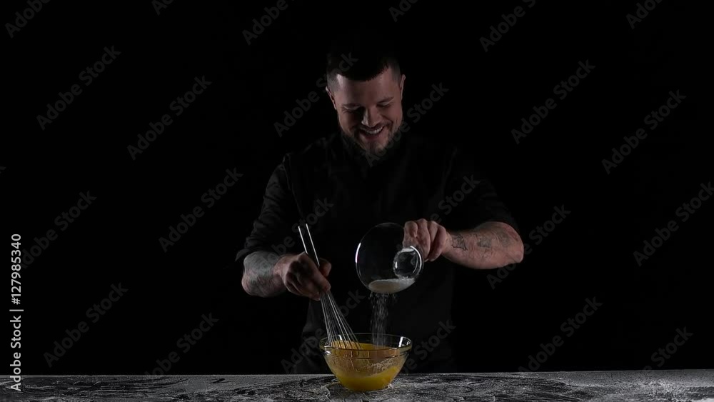 chef mixes the eggs with the sugar black background.