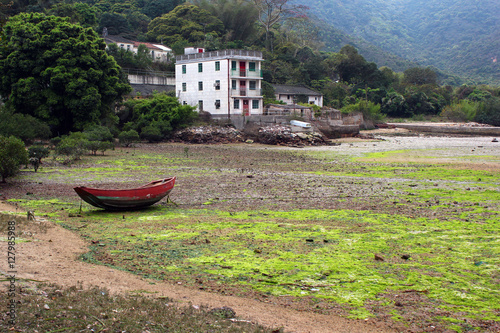 Low tide in abandoned village of Chek Keng, Hong Kong. Fishing boat on the ground photo