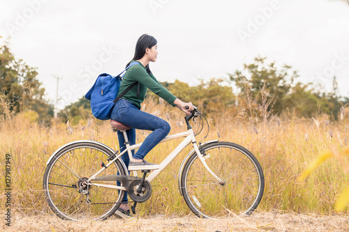 Teenager girl, bicycle with flowers basket in outdoor landscape
