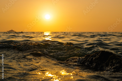 sea wave close up at sunset time with red and orange sun reflection on the water. nature abstract blurred background. Phuket island, Thailand