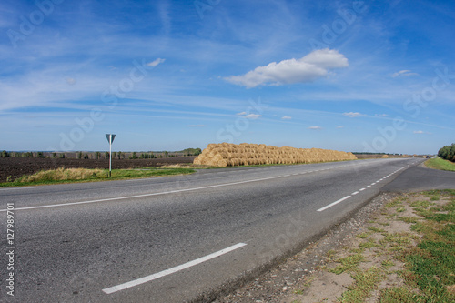 Big haystack and a road daytime landscape