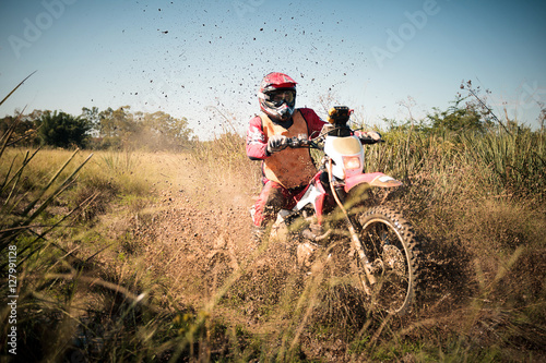 Off road dirt bike rider splashing mud in hard enduro rally race