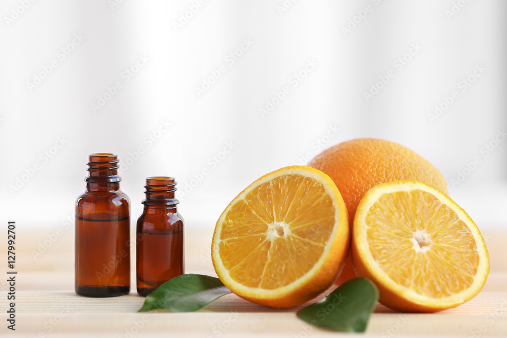 Bottles with essential oil, oranges and leaves on wooden table Bottles with essential oil, oranges and leaves on wooden table