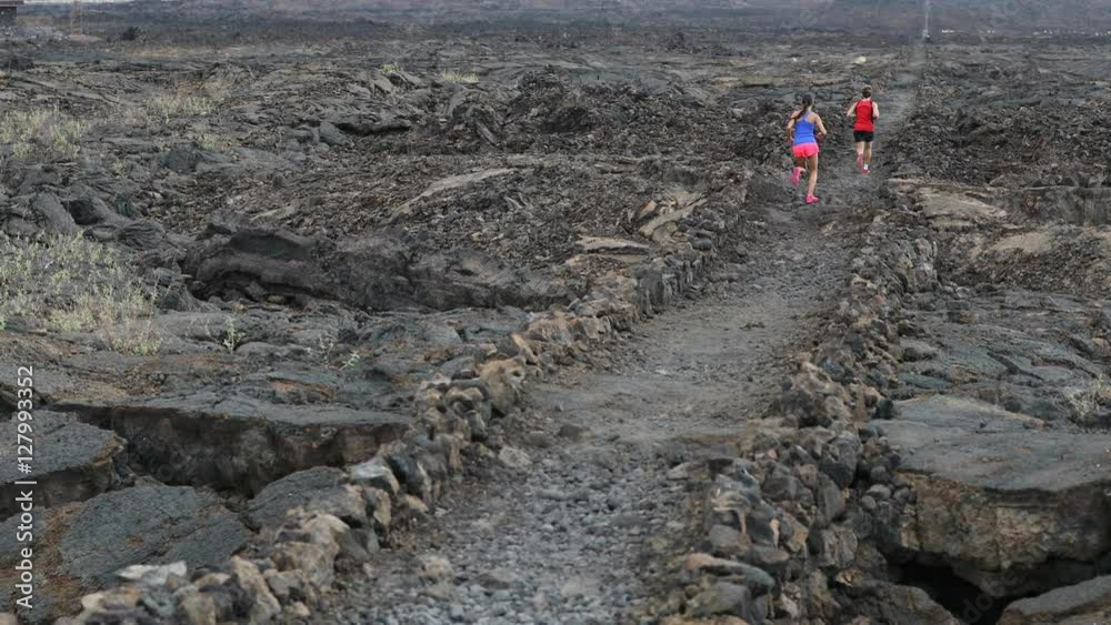 Cross country running woman and man trail runners jogging training outdoors for marathon or triathlon run in beautiful volcano landscape nature. Athlete couple working out on Big Island, Hawaii. Cross country running woman and man trail runners jogging training outdoors for marathon or triathlon run in beautiful volcano landscape nature. Athlete couple working out on Big Island, Hawaii.