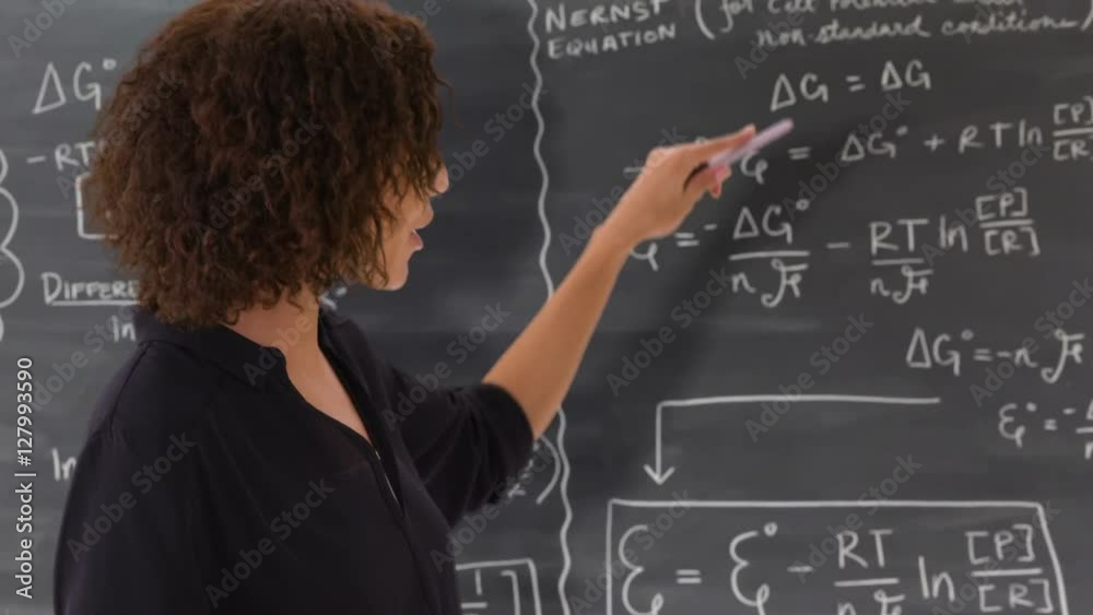 Portrait of black teacher giving math lesson on chalkboard.