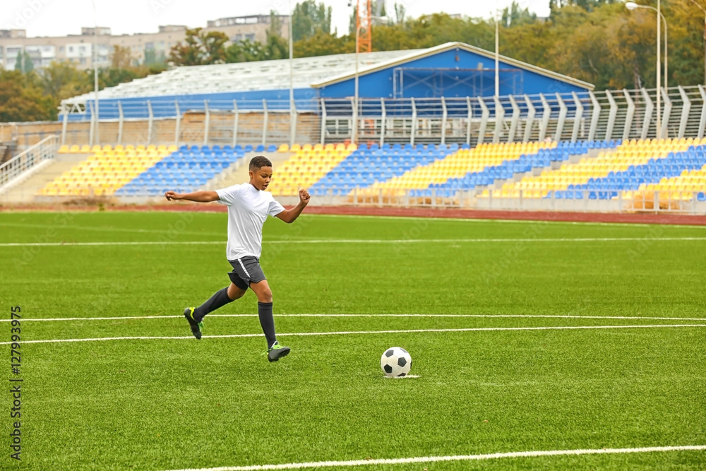 Fototapeta premium Boy playing football at stadium
