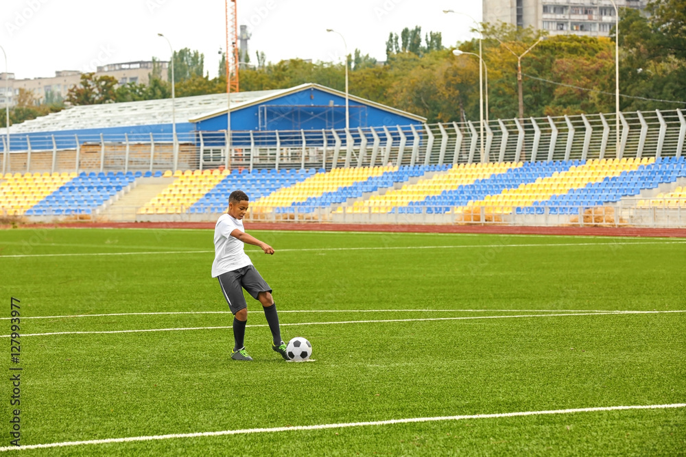 Fototapeta premium Boy playing football at stadium