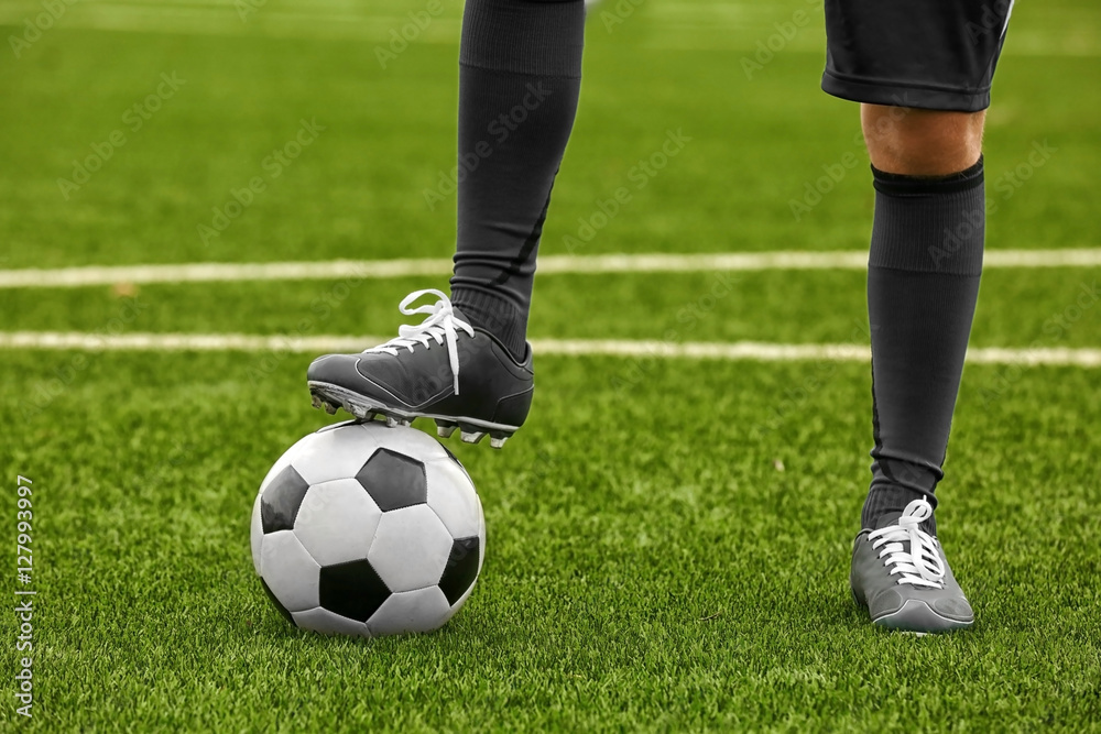 Football player holding ball with foot, closeup