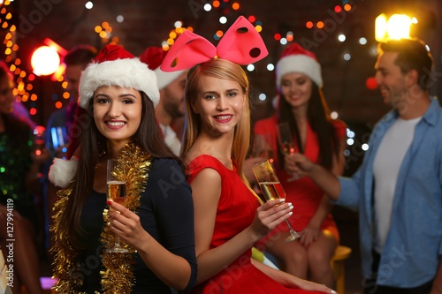 Young women with glasses of champagne at Christmas party