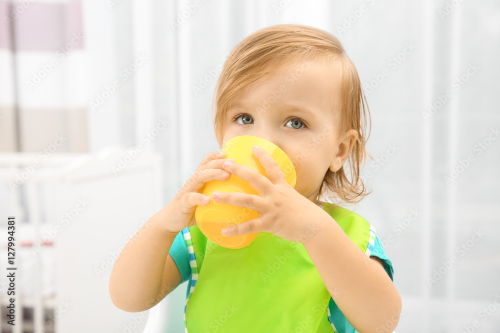 Cute little girl drinking juice in high chair at baby room Cute little girl drinking juice in high chair at baby room