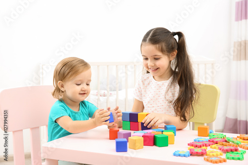 Cute girl playing with little sister at home