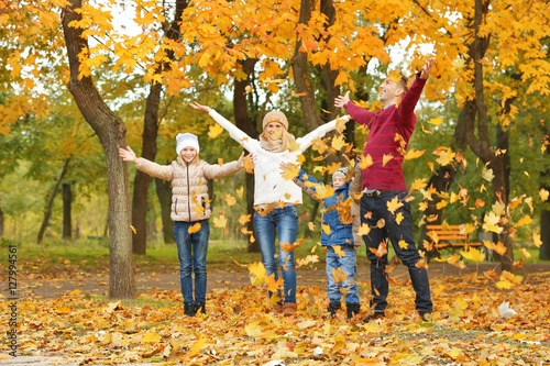 Happy family playing with leaves in beautiful autumn park