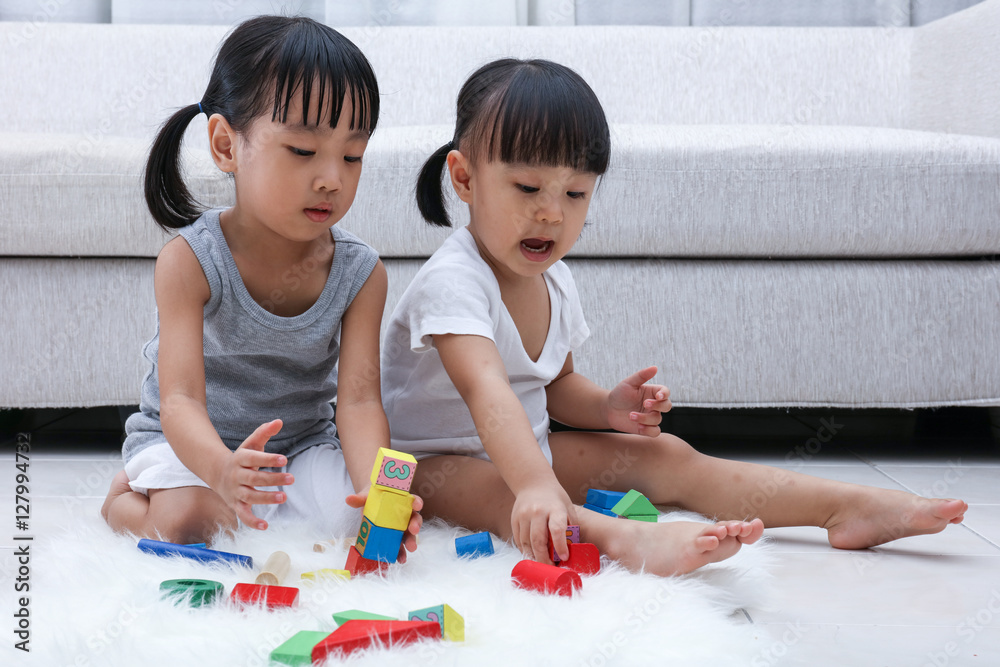 Asian Chinese little sisters playing blocks on the floor Asian Chinese little sisters playing blocks on the floor