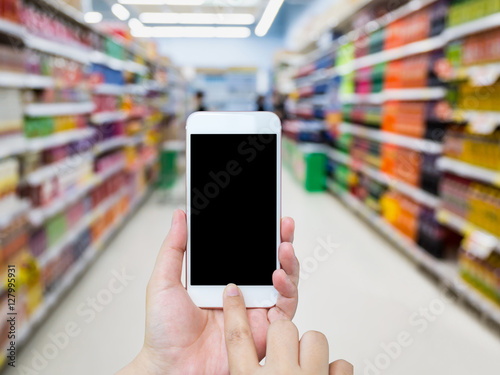 Female using mobile smart phone with Supermarket Aisle backgroun