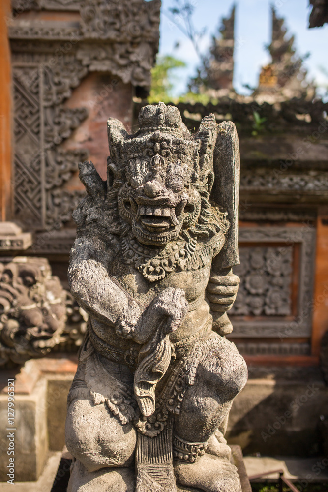 Traditional guard demon statue carved in dark stone on Bali island