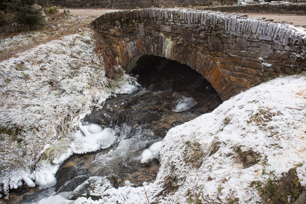 Old ancient bridge over a stream with frozen shores in the High Tatras. Old ancient bridge over a stream with frozen shores in the High Tatras.