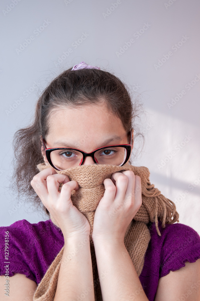 Girl covers her mouth with a scarf with both hands Girl covers her mouth with a scarf with both hands