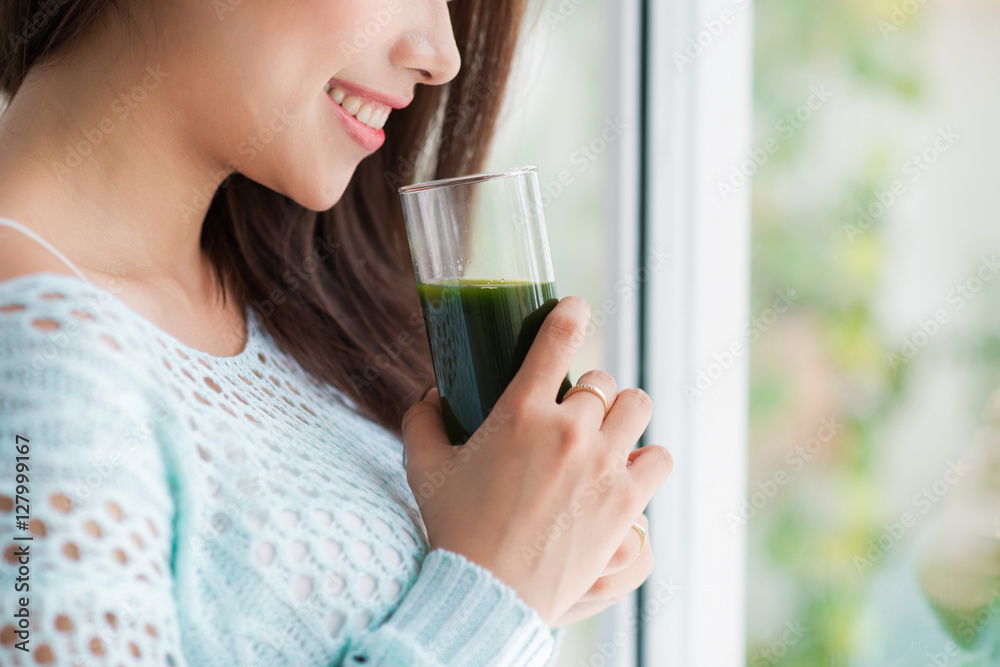 Smiling young asian woman drinking green fresh vegetable juice o Smiling young asian woman drinking green fresh vegetable juice o