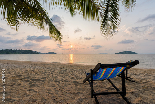 Beach chairs on beach with beautiful beach and tropical sea at sunset.