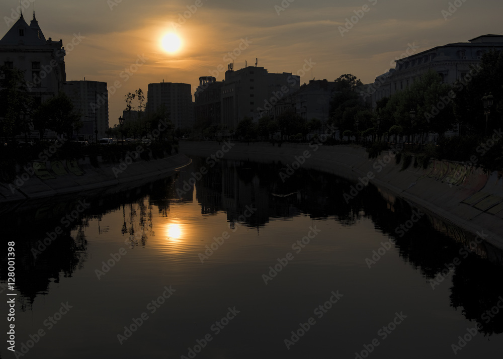 Abstract city skyline. Sunset time view of city of Bucharest, reflected in Dambovita River.