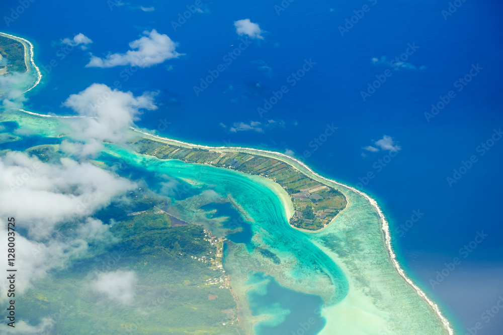 Aerial view of the island with clouds, reef and lagoon. Island n