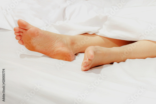 Under the covers with feet showing in a bed © Adul10