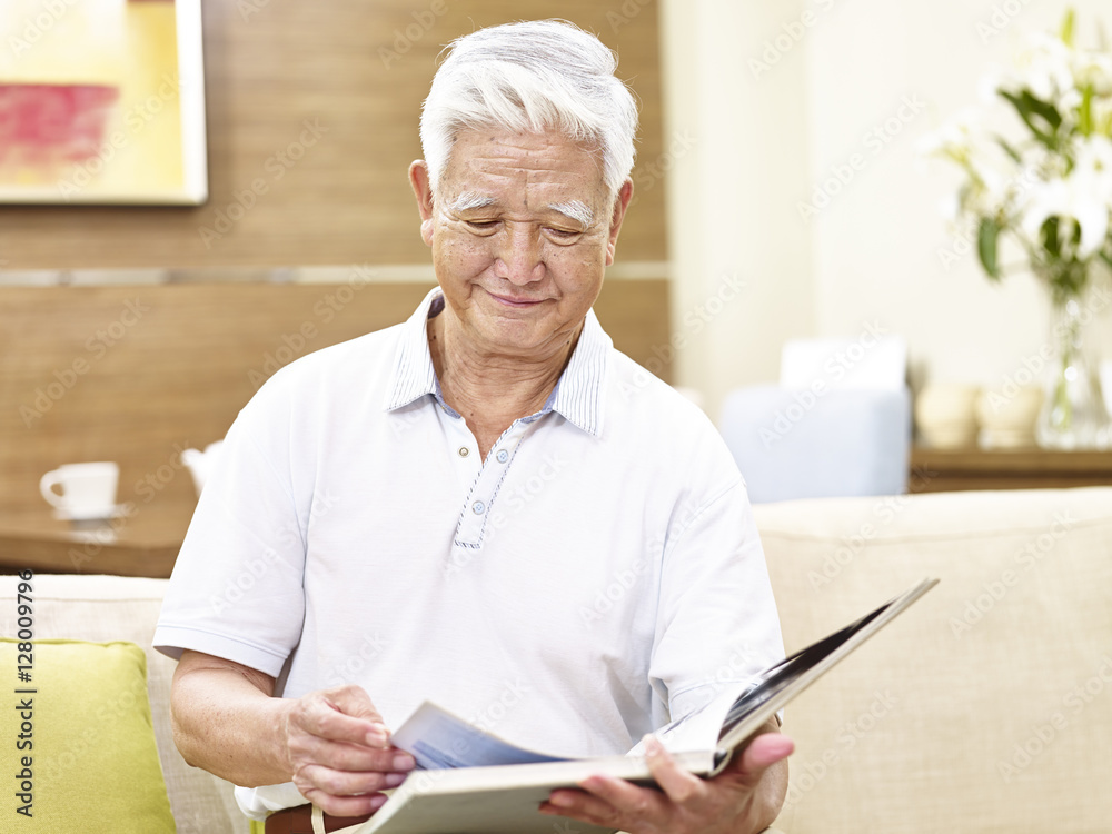 senior asian man relaxing reading a book at home senior asian man relaxing reading a book at home