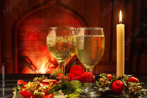 Christmas card, a glass of champagne and Christmas candle on the background of the fireplace