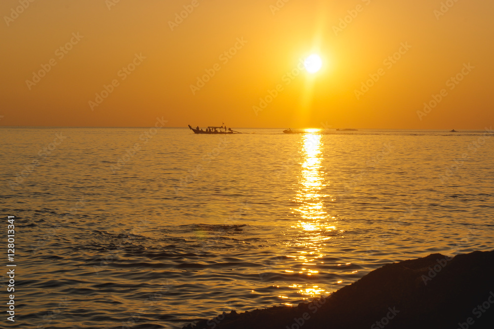 amazing tropical orange sunset over water, with rock silhouettes on Phuket Island, Thailand,