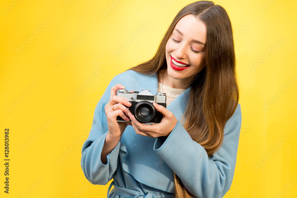 Stylish woman photographer with retro camera on the yellow wall background Stylish woman photographer with retro camera on the yellow wall background