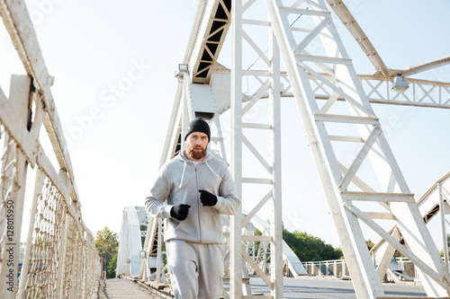 Attractive young bearded sportsman running across the bridge
