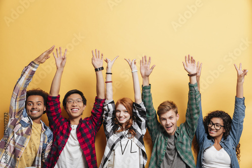 Happy young people standing and celebrating success with raised hands