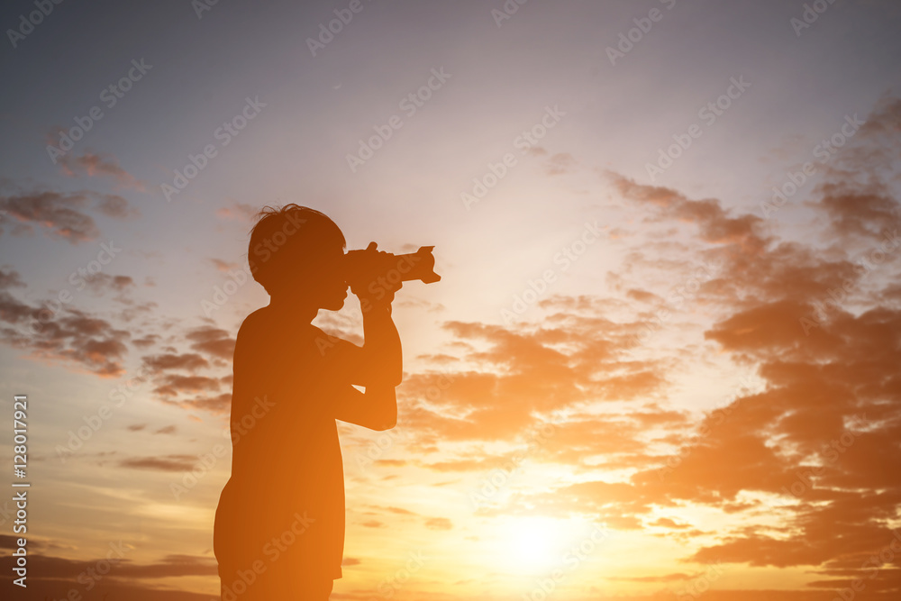 Silhouette of a young man  holding camera, extend the arms while