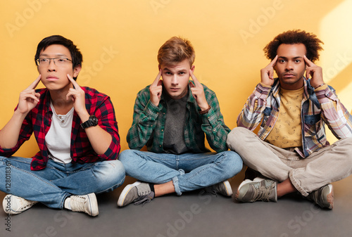 Three tensed stressed young men friends sitting and touching temples