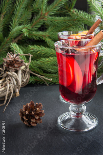 Christmas drink. Hot Mulled wine with cinnamon and christmas tree on black slate dish. Close up, copy space.