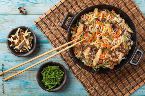 Rice noodles with chicken, mushrooms mun and vegetables in wook. photo