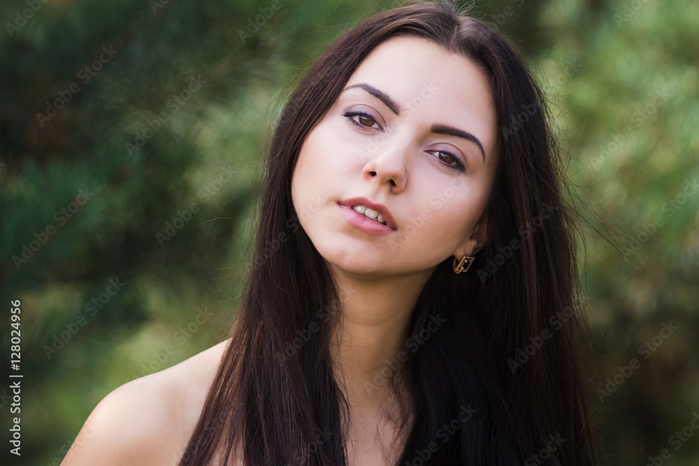 Graceful charming brunette model posing in black dress in coniferous park Graceful charming brunette model posing in black dress in coniferous park