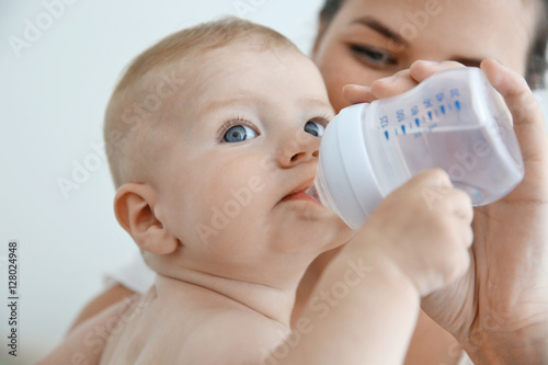 Mother giving to drink water baby from bottle, closeup