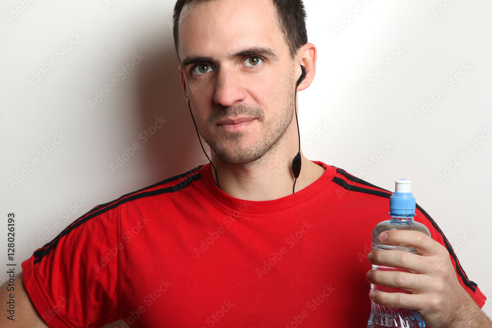 Young athletic man holding a bottle of water. The concept of sport and a healthy lifestyle.