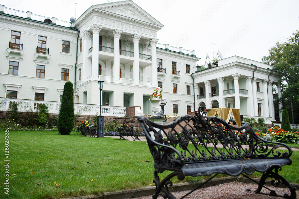 Black steel bench stands before white luxurious white house Black steel bench stands before white luxurious white house