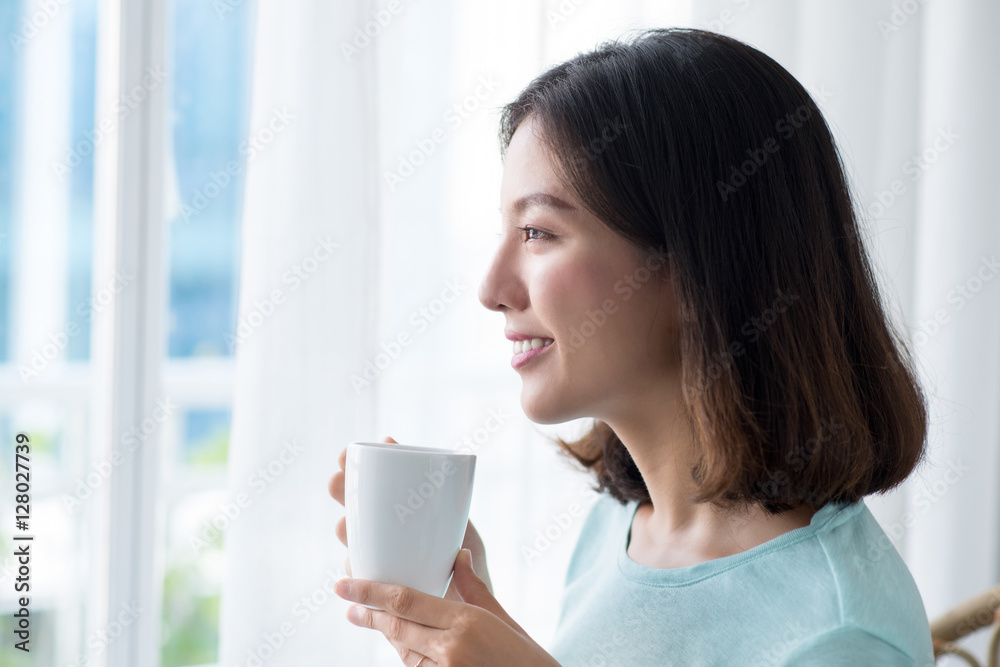 Young pretty woman sitting at opened window drinking coffee and Young pretty woman sitting at opened window drinking coffee and