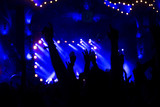 silhouettes of concert crowd in front of bright stage lights
