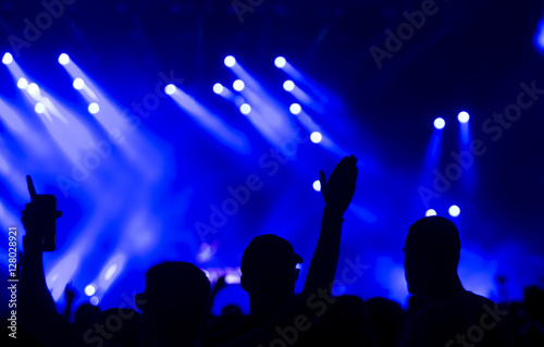 silhouettes of concert crowd in front of bright stage lights 