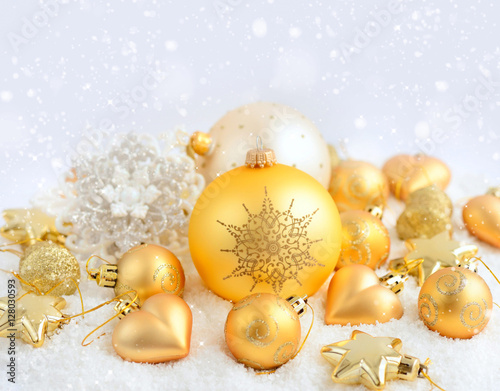 Christmas gold ornaments on the snow. Festive Christmas background