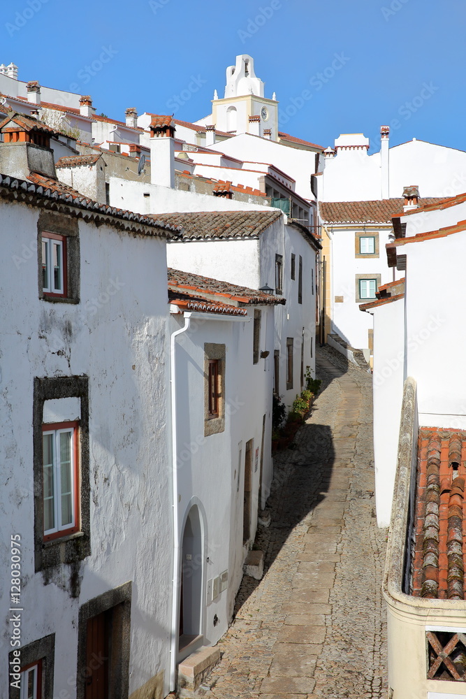 MARVAO, PORTUGAL: A typical cobbled street with whitewashed houses and tiled roofs with the Clock Tower in the background