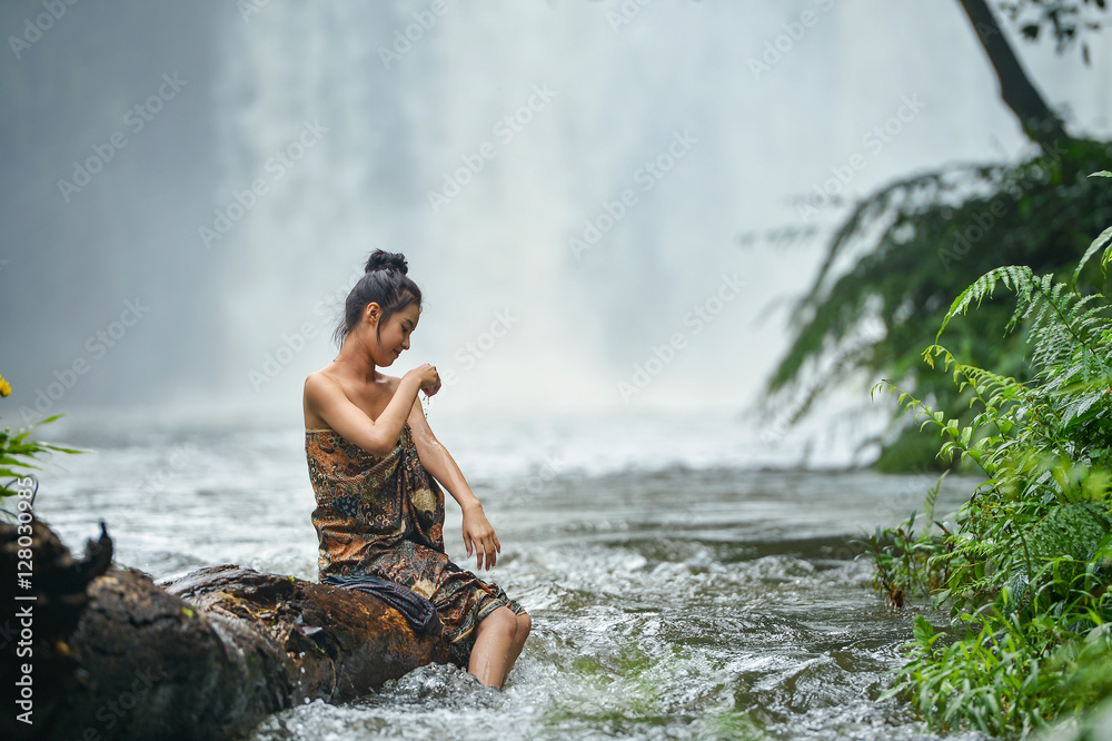 Asian woman wearing traditional thai take a baht on during sunset